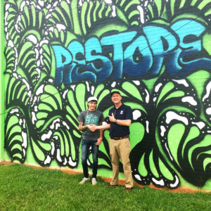 Artist standing in front of the mural with Habitat rep