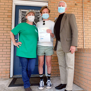 Volunteer Elle Forbes, realtor Jarrett Martin with donation check, and Athens Habitat VP Charles Smith on the front porch of the Habitat office in Athens, GA
