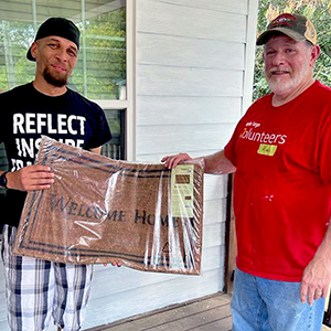 Volunteers from Wells Fargo donate a welcome mat to the new homeowners on their volunteer day