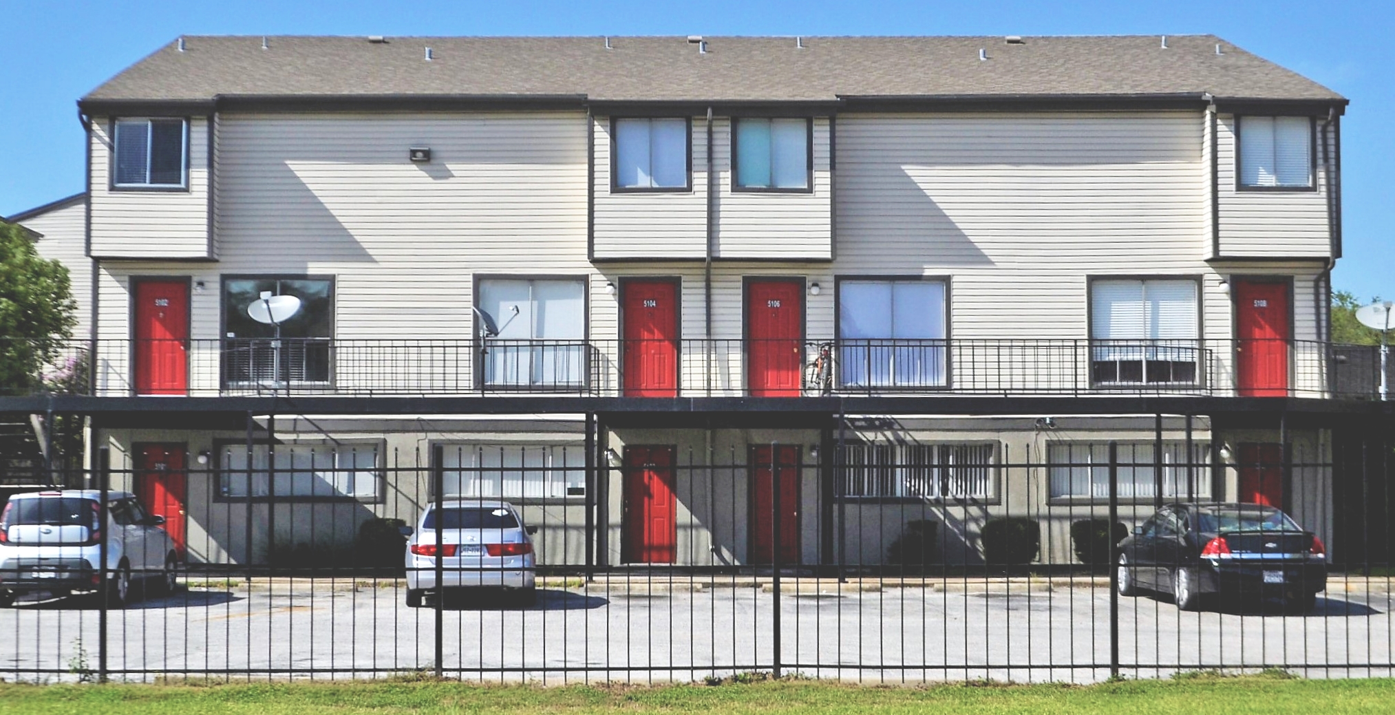 Small apartment building with 3 cars parked out front