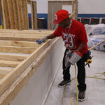 A worker assembles a wall in an Impact Housing plant