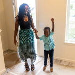 A little boy jumps as he enters a new house with his mom