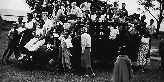 Families at Koinonia Farms assemble around a car for a group photo