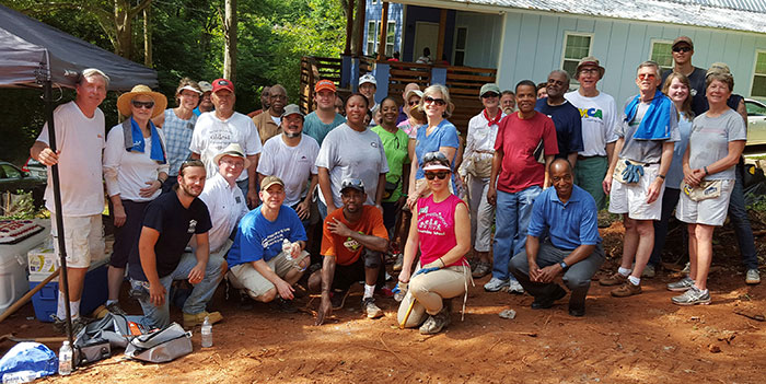 Habitat crew, homeowners, and volunteers pose for a photo at a Habitat construction site