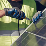 A technician uses a screwdriver to install a solar panel