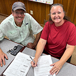 A new homeowner signs paperwork with the Habitat affiliate director